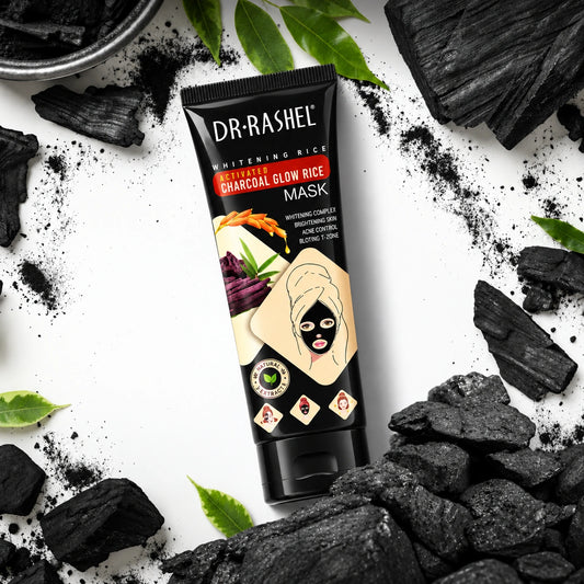DR·RASHEL Activated Charcoal Glow Rice Mask tube with charcoal chunks, charcoal powder, and green leaves on a white background.