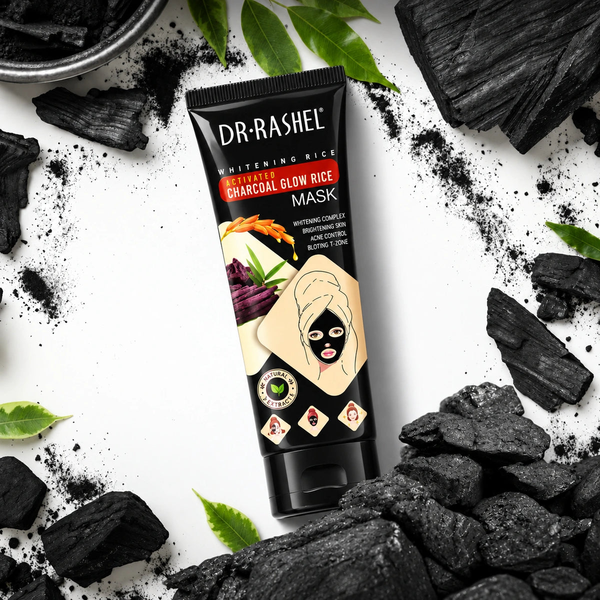 DR·RASHEL Activated Charcoal Glow Rice Mask tube with charcoal chunks, charcoal powder, and green leaves on a white background.