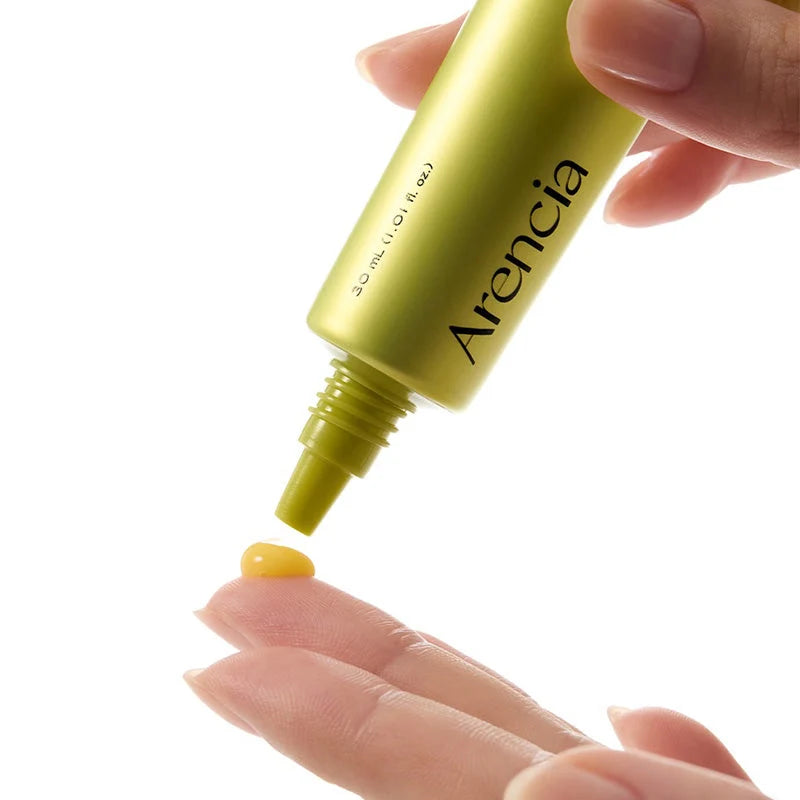 Hand holding a yellow cosmetic product labeled 'Arencia' against a white background